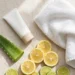 Flat-lay photograph of sunscreen, aloe leaf and citrus on a light background