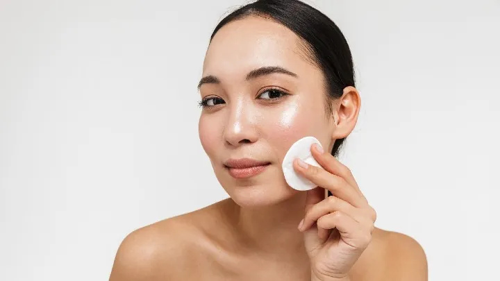 Woman applying facial toner to her face