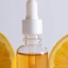 Glass serum dropper bottle with fresh orange slices