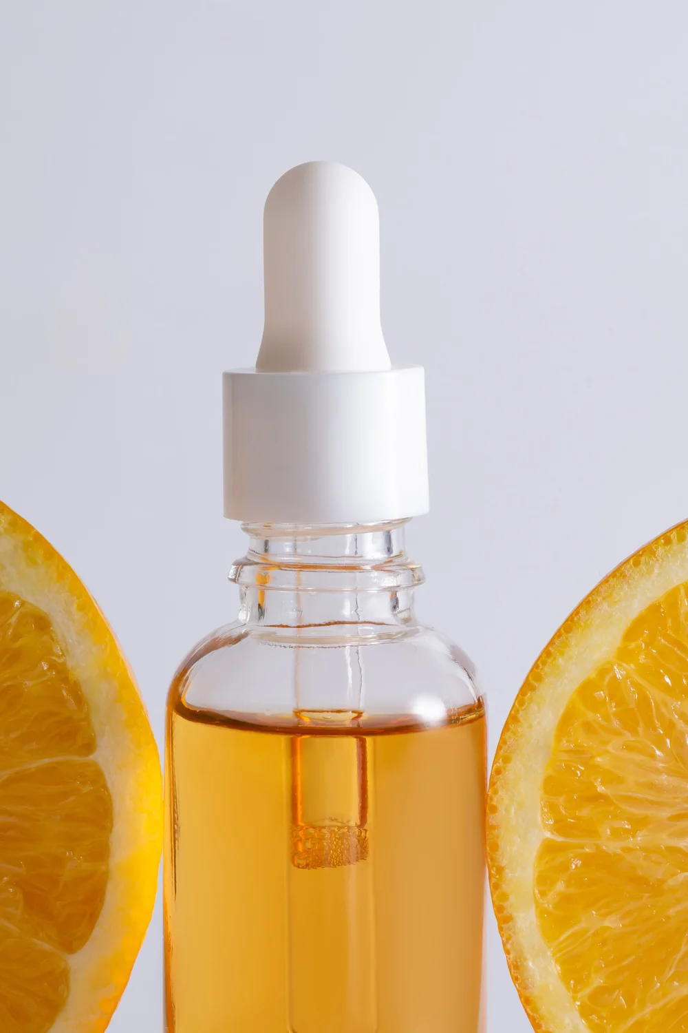 Glass serum dropper bottle with fresh orange slices