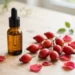 Amber dropper bottle of rosehip oil with rose hips and petals on wood