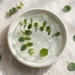 Ceramic dish with translucent skincare gel and fresh green leaves
